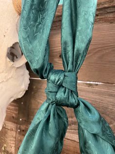 a close up of a green scarf on a wooden surface with a skull in the background