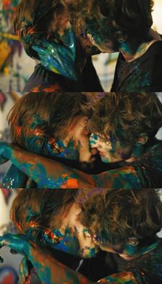 two people covered in colorful paint are kissing each other