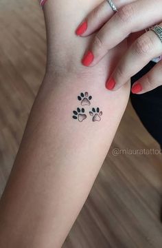 a woman's arm with a small paw tattoo on the left side of her arm