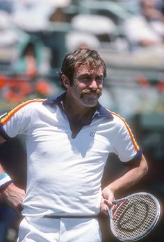 a man holding a tennis racquet on top of a tennis court with people in the background