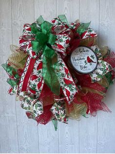 a christmas wreath hanging on the side of a door with red, green and gold mesh