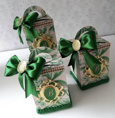 three boxes with green bows on them sitting next to each other in front of a white background