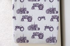 a towel with tractors on it hanging from the wall next to a toilet paper dispenser