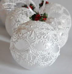 three white ornaments with red flowers on them