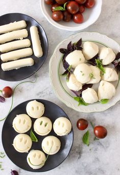 two black plates with mozzarellas and cherry tomatoes on them, along with other food items