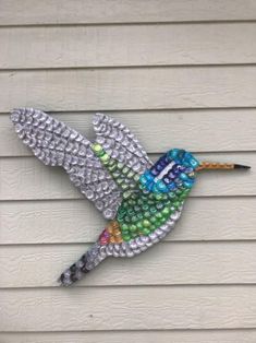 a colorful bird made out of beads on the side of a house