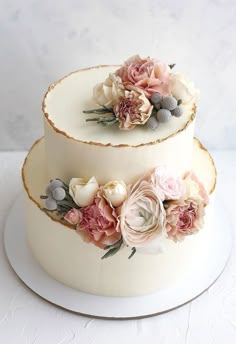 two tiered wedding cake with flowers on each layer and white frosting icing