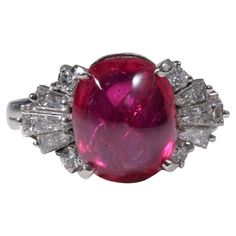 An enormous, spectacular four-carat cabochon-cut vivid pinkish-red no-heat Burma ruby commands attention in this extraordinary platinum Mid-century ring. The stoplight-red ruby measures 10.33mm x 8.74mm x 4.84mm and weighs 4.75 carats. Three sleek tapered baguette diamonds and a pair of round brilliants compliment the ruby on either side. Together the diamonds weigh approximately .25 carats. The diamonds are bright white (F/G) and near-flawless (VS1). This exceedingly rare and important stone ca Luxury Vintage Oval Cabochon Ruby Ring, Elegant Luxury Cabochon Diamond Ring, Luxury Cabochon Round Cut Rings, Luxury Cabochon Ruby Ring, Luxury Red Cabochon Ruby Ring, Formal Red Ruby Ring In Platinum, Red Ruby Ring, Beautiful Tiaras, Ruby Diamond Rings