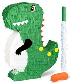 a paper cut out of a green dinosaur with its mouth open next to a carrot