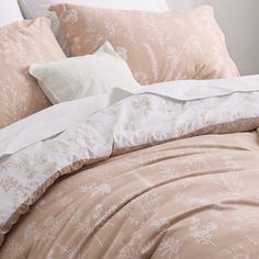 an unmade bed with pink and white comforters