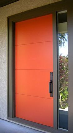 an orange front door on a house with glass and metal frame, in the day light