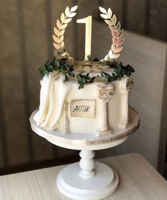 a white cake with gold decorations on top and the number one on it's side