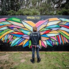 a person standing in front of a wall with a large colorful butterfly painted on it