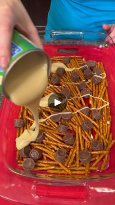 a person pouring milk on some pretzels in a red container with chocolate chips