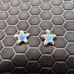 two small silver stars with blue and white oplites in them on a black surface