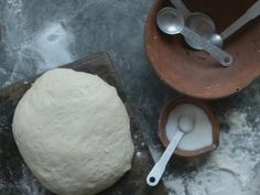 a ball of dough sitting on top of a wooden table next to measuring spoons