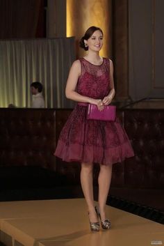 a woman in a red dress holding a pink purse and standing on a yellow carpet