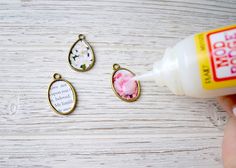 three charms that have flowers on them and one is being used as a glue bottle