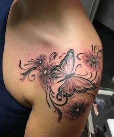 a woman's shoulder with a butterfly tattoo on it and flowers around the arm