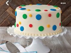 a white cake with multicolored polka dots on it and a spoon next to it