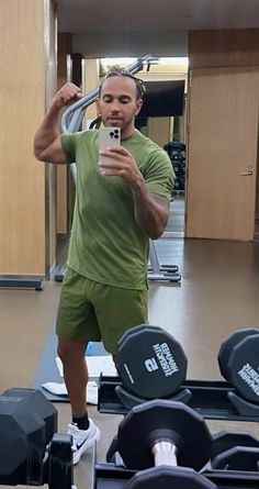 a man taking a selfie in the gym with his cell phone and dumbbells