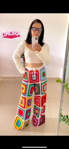 a woman taking a selfie in front of a mirror wearing colorful pants and sweater