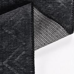 the corner of a piece of black fabric with white stitching on it and an area for