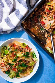 a white plate topped with food next to a pan filled with rice and other foods