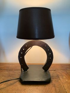 a table lamp sitting on top of a wooden table next to a black lampshade