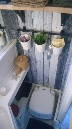 a small bathroom with a toilet, sink and shelf above it is decorated in wood planks