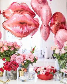 pink balloons and flowers on a table with lipstick shaped balloons in the shape of lips