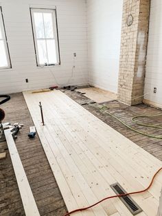 an unfinished room with wood flooring being laid on the ground and wires attached to the wall