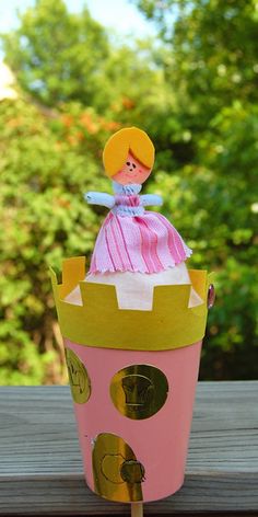 a paper doll sitting on top of a pink princess's castle with trees in the background