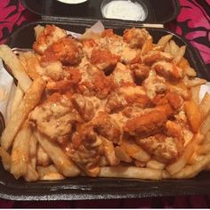 a tray filled with french fries covered in meat and cheese sauce next to dipping sauce