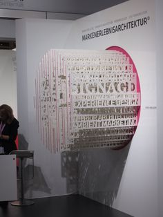 a woman standing in front of a white wall with red and black letters on it