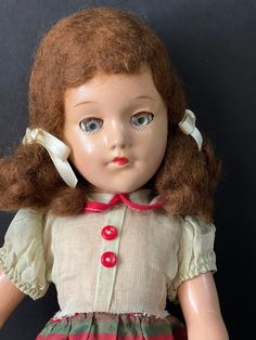 a doll with brown hair wearing a red and white striped dress on a black background