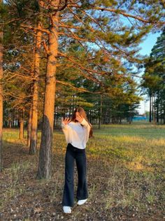 a woman standing in the woods taking a photo