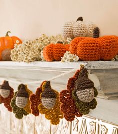 crocheted pumpkins and gourds are hanging on the mantle