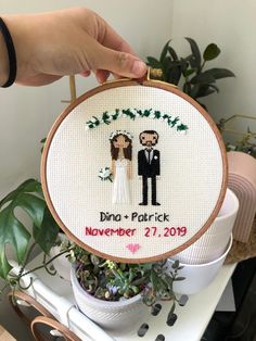 a cross - stitch bride and groom are holding their wedding date on the back of an embroidered hoop