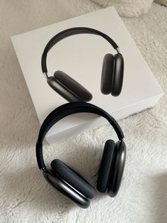 two black headphones sitting on top of a white box next to a pair of ear buds