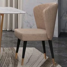 a beige chair sitting on top of a rug next to a white table with a marble top