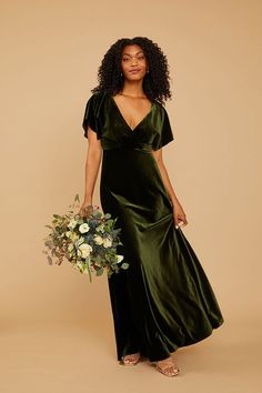 a woman in a green dress holding a bouquet