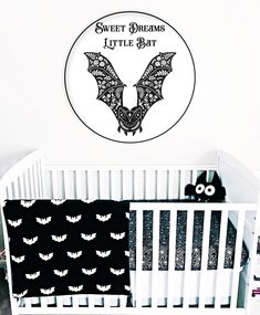 a white crib with a black and white bat wall decal next to it