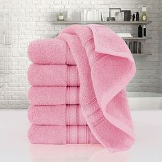 a stack of pink towels sitting on top of a white counter next to a brick wall