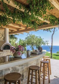 an outdoor bar with stools and potted plants on the counter next to it