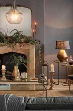 a living room filled with furniture and a fire place covered in greenery next to a mirror