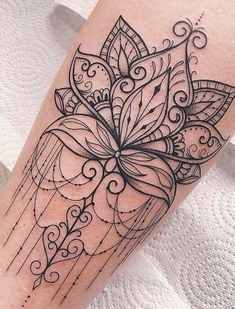 a black and white photo of a tattoo on the leg with an intricate flower design