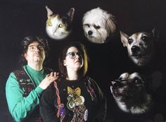 two people standing next to each other with dogs and cats on their heads in front of them