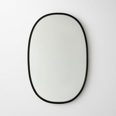 an oval shaped mirror on the wall with black trim around it's edges and bottom edge