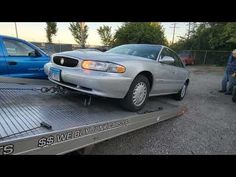 a silver car is on the back of a flatbed tow truck